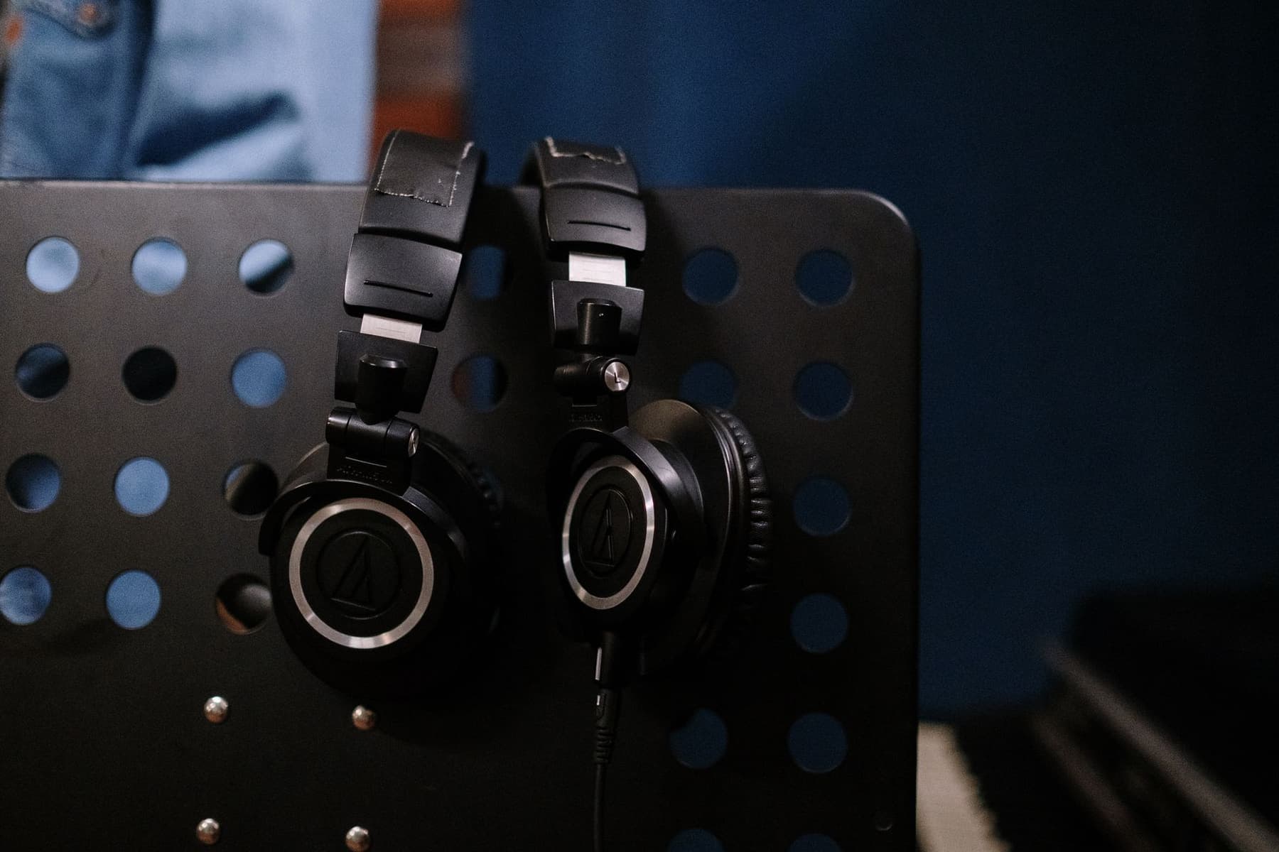 A pair of large studio headphones hanging on a stand