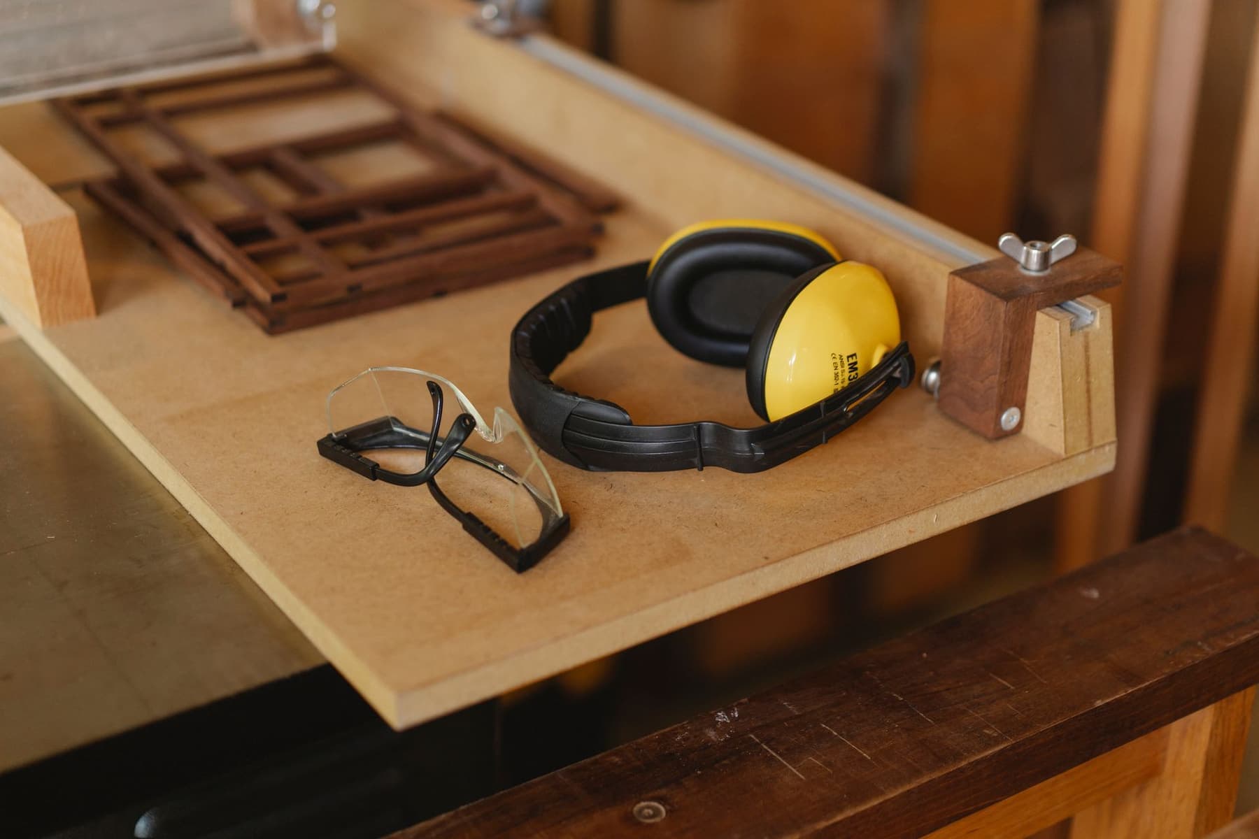 Protective over-ear defenders and safety glasses on a wooden workbench