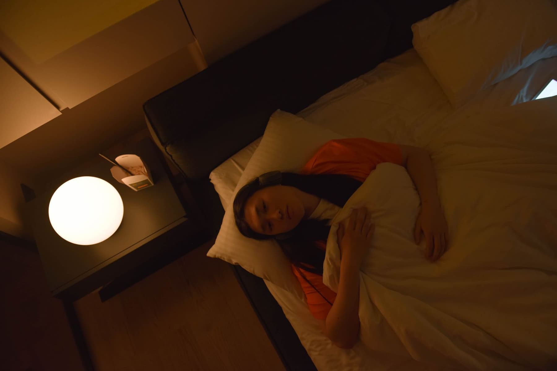 A person lying awake in dim light wearing headphones