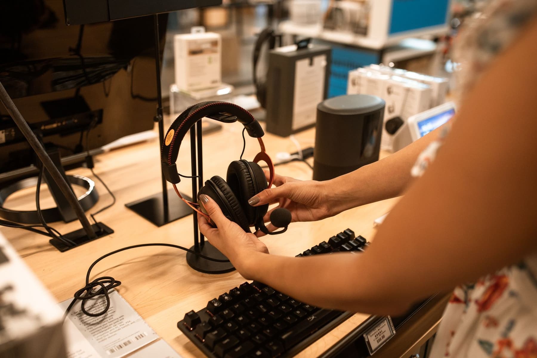 A shopper examining a pair of headphones on a display in an electronics store