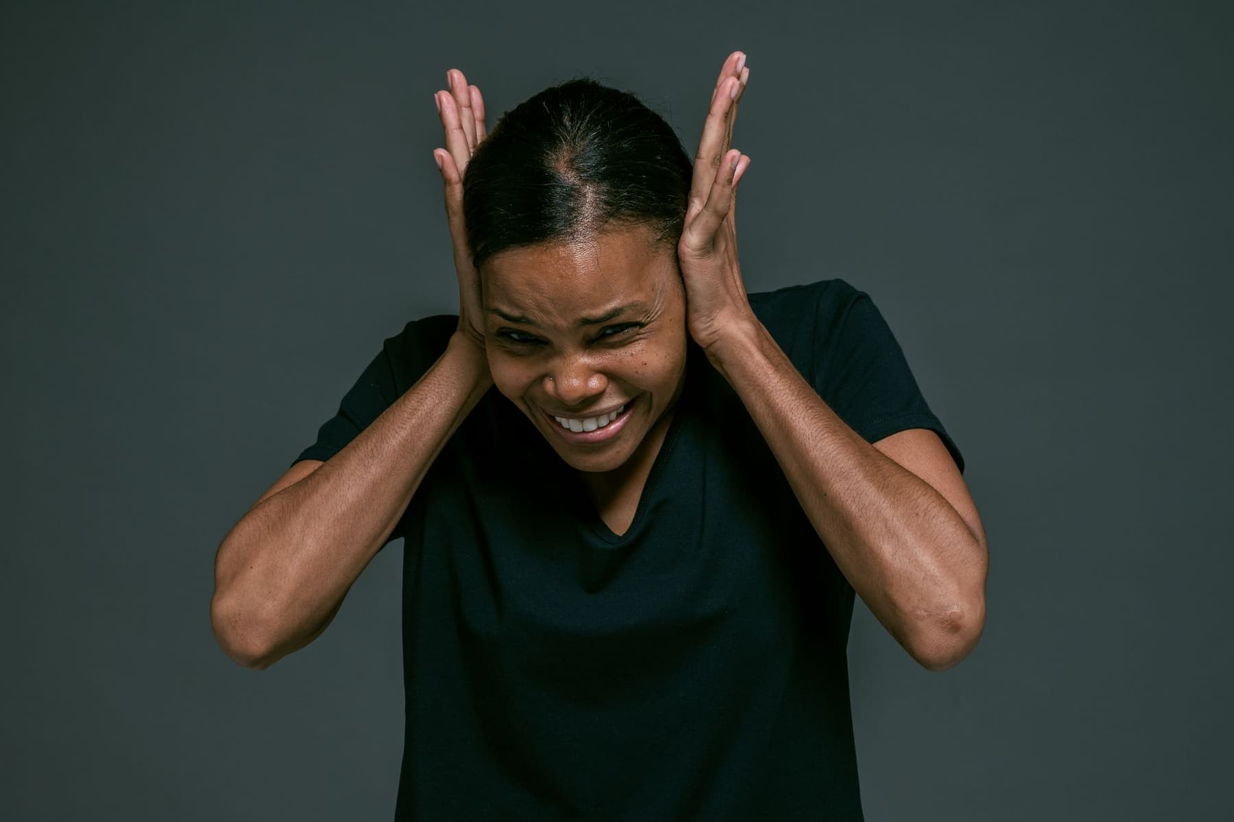 A person covering their ears with both hands, looking uncomfortable