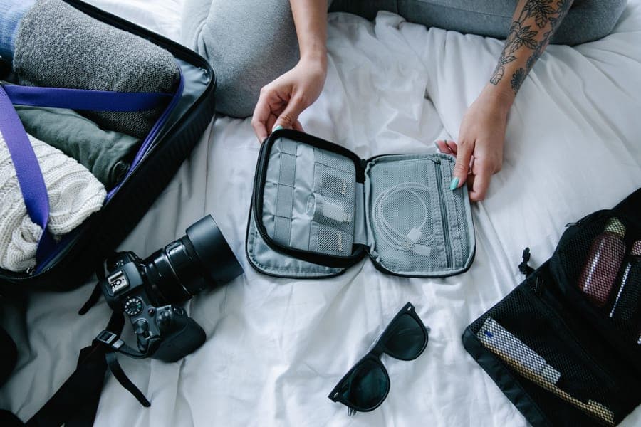 A traveler organizing essentials and packing cubes on a bed