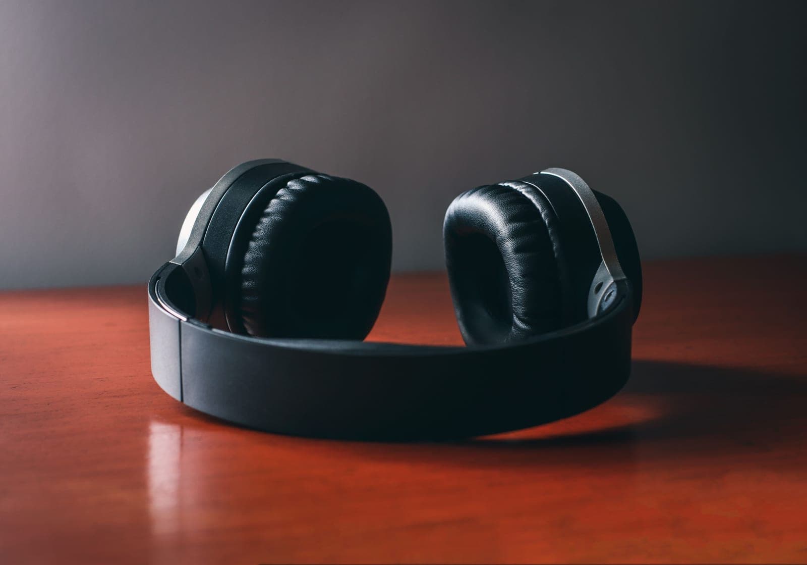 Wireless over-ear headphones resting on a polished wooden surface