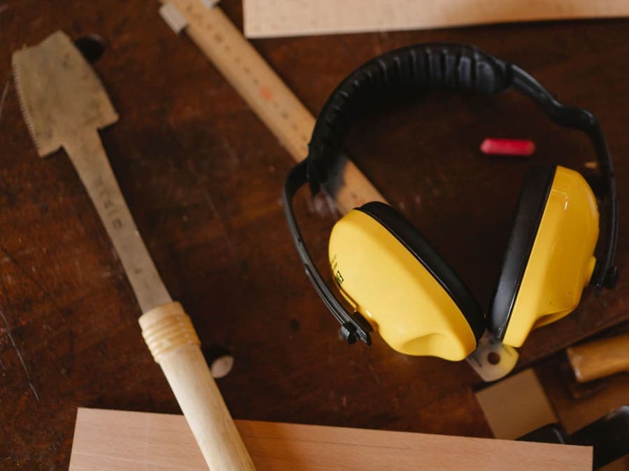 Bright noise-reducing ear defenders resting on a wooden workbench