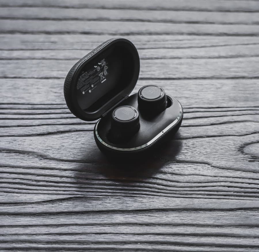 Wireless noise canceling earbuds in an open charging case on a wooden surface
