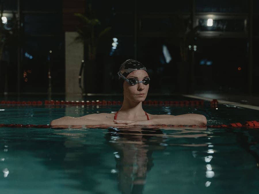 A swimmer in cap and goggles training in an indoor lane pool