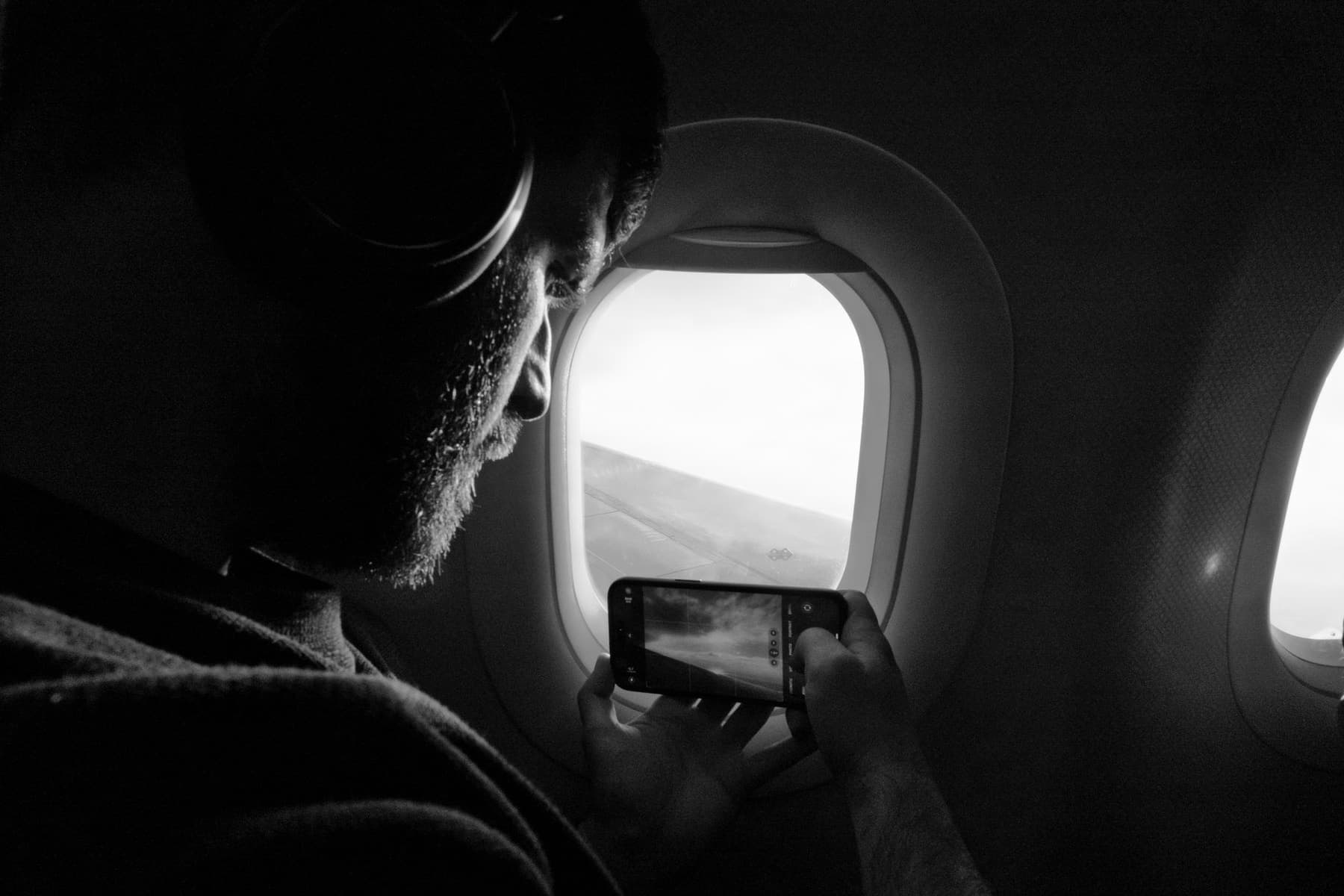 A passenger seated at an airplane window looking out over the wing