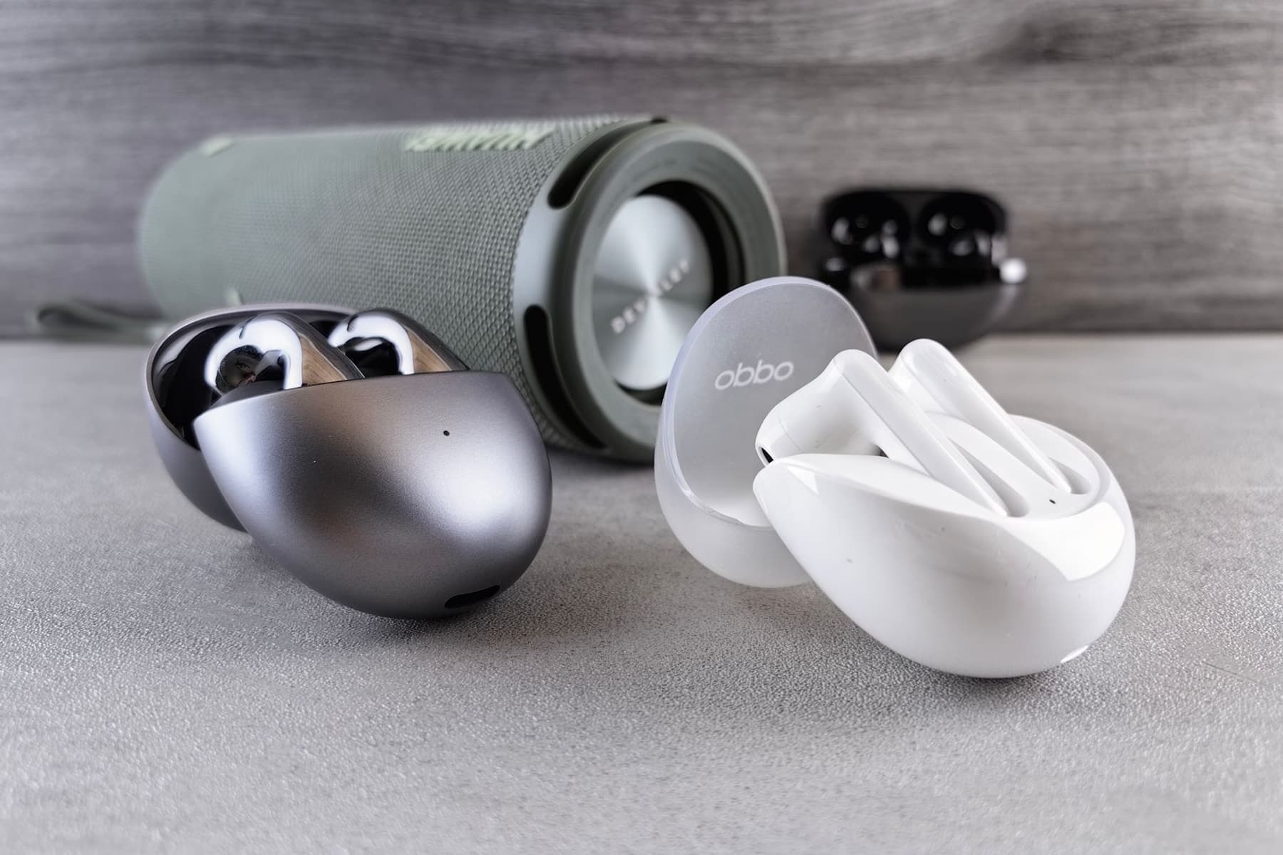 Two sets of true wireless earbuds displayed side by side on a modern surface