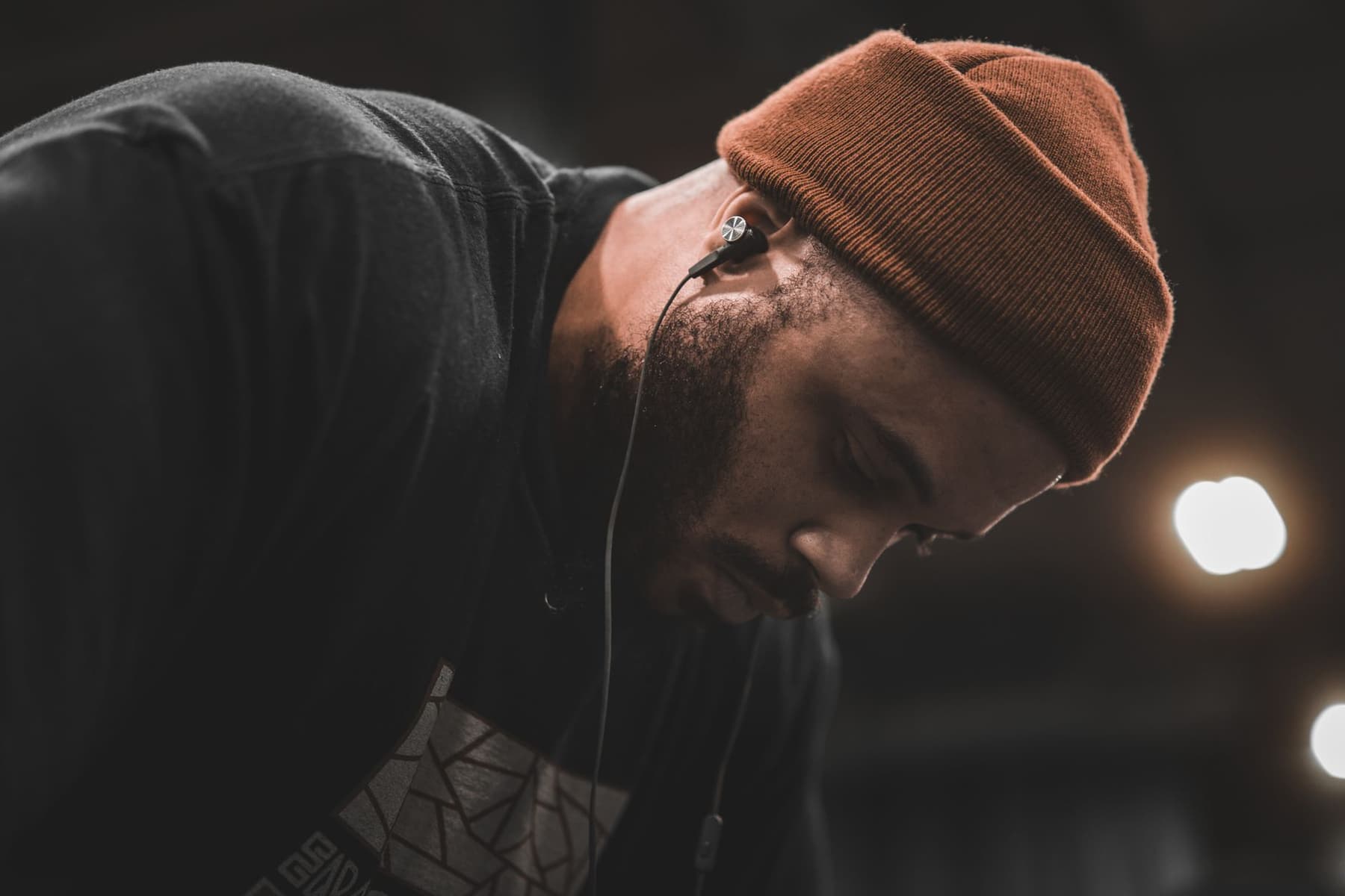 A man in a beanie wearing over-ear headphones in dim light