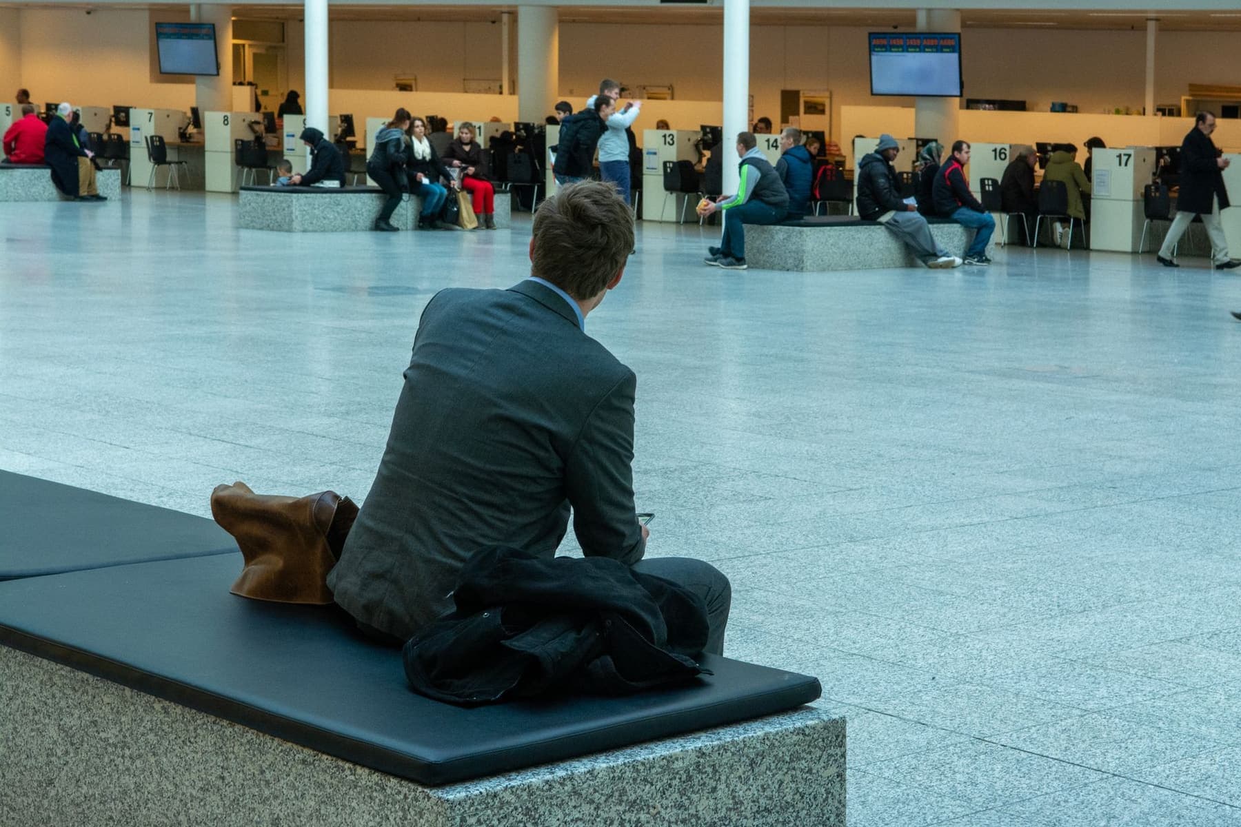 A businessman in a suit seated in an airport terminal waiting area