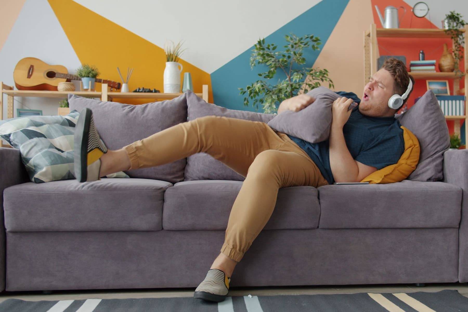 A person relaxing on a couch wearing padded over-ear headphones