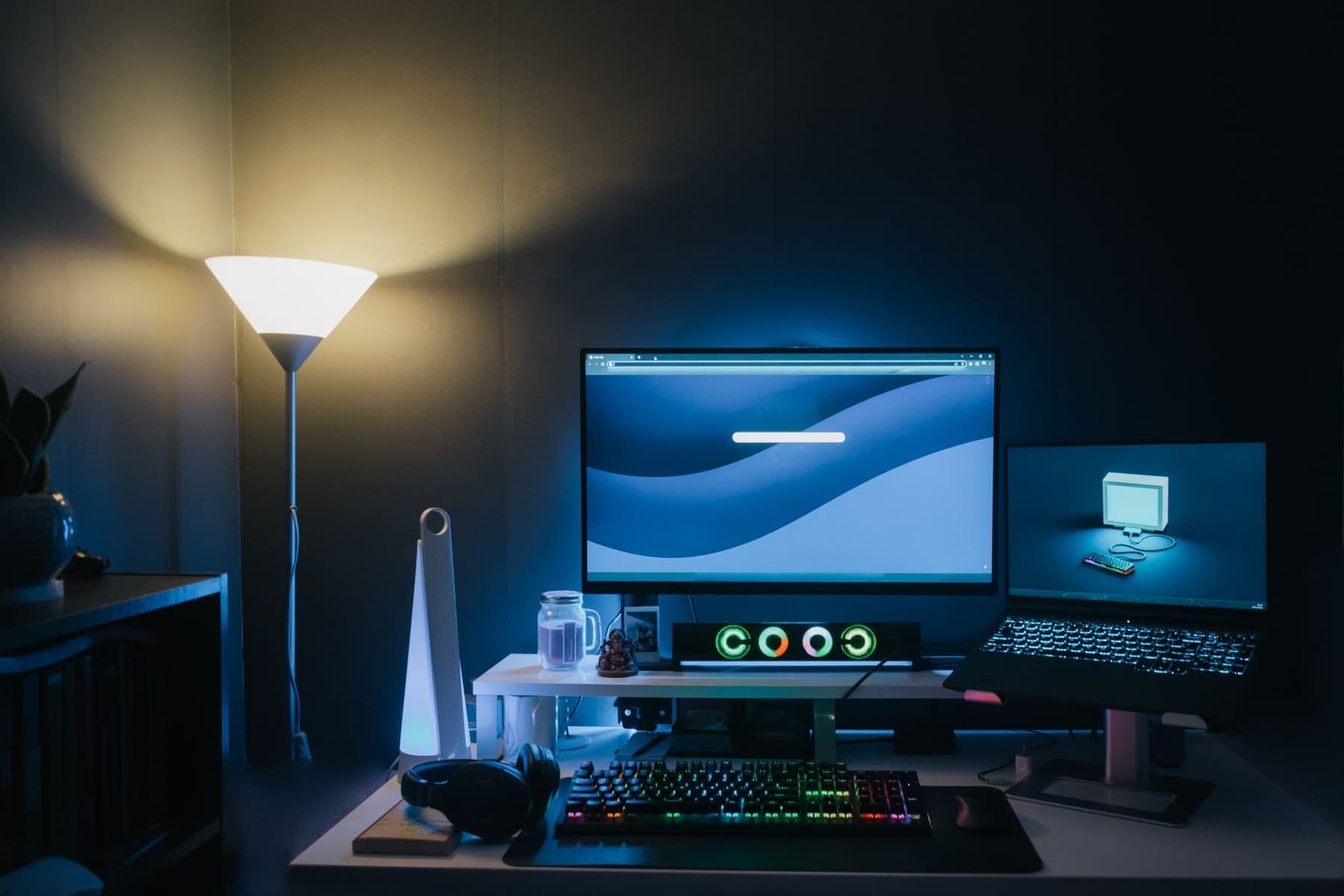 A gaming desk setup with a monitor and keyboard lit at night
