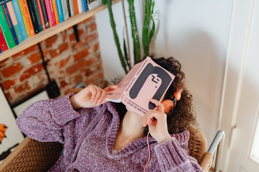 A person relaxing with a book and headphones in a comfortable indoor setting