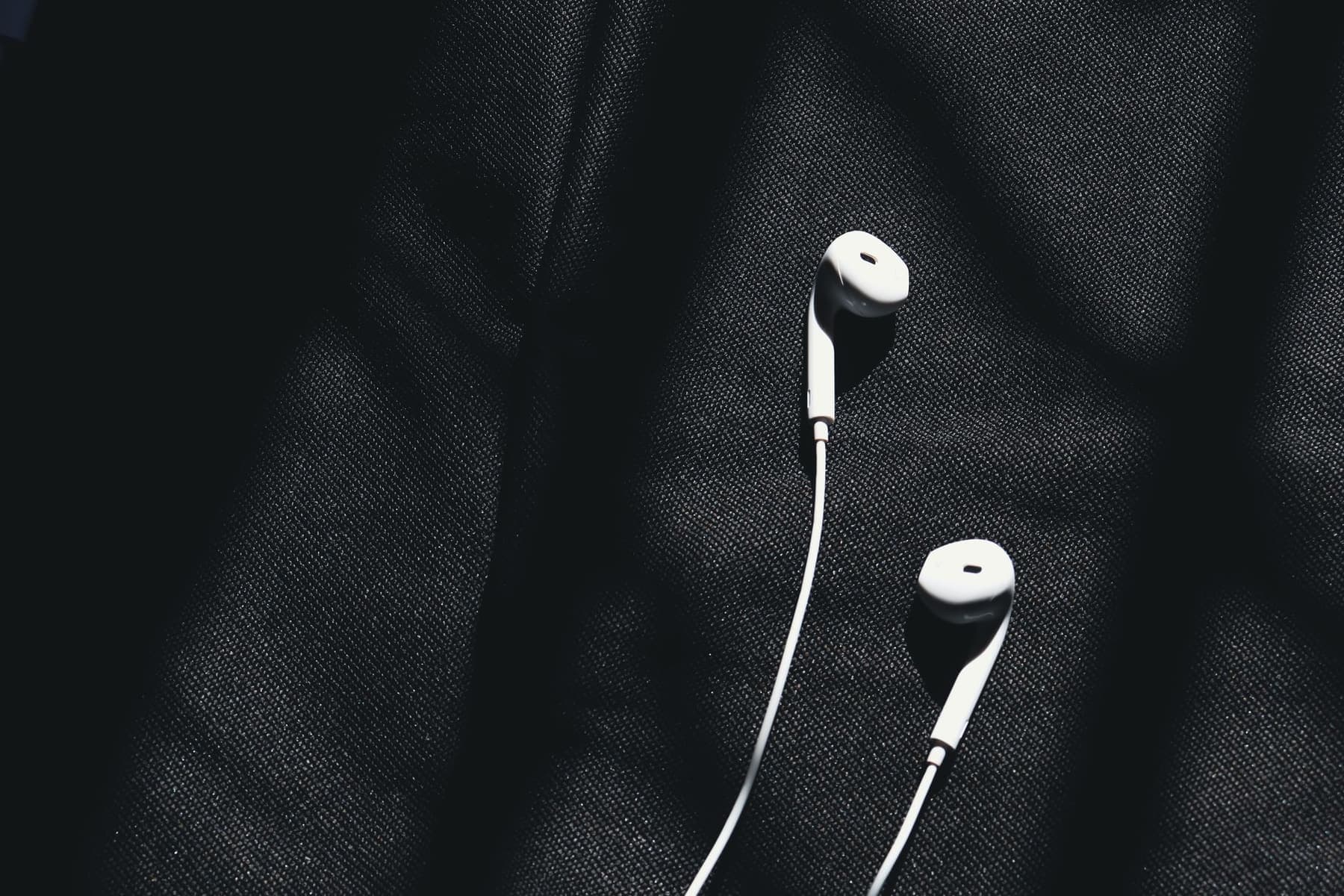 Wired in-ear earphones coiled on a dark surface