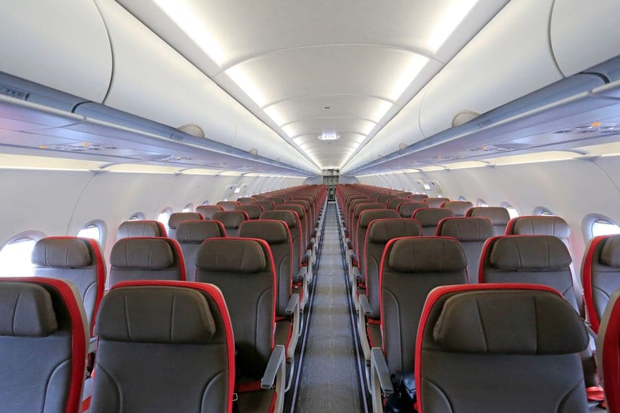 Wide view of an aircraft cabin with empty rows of seats ready for boarding