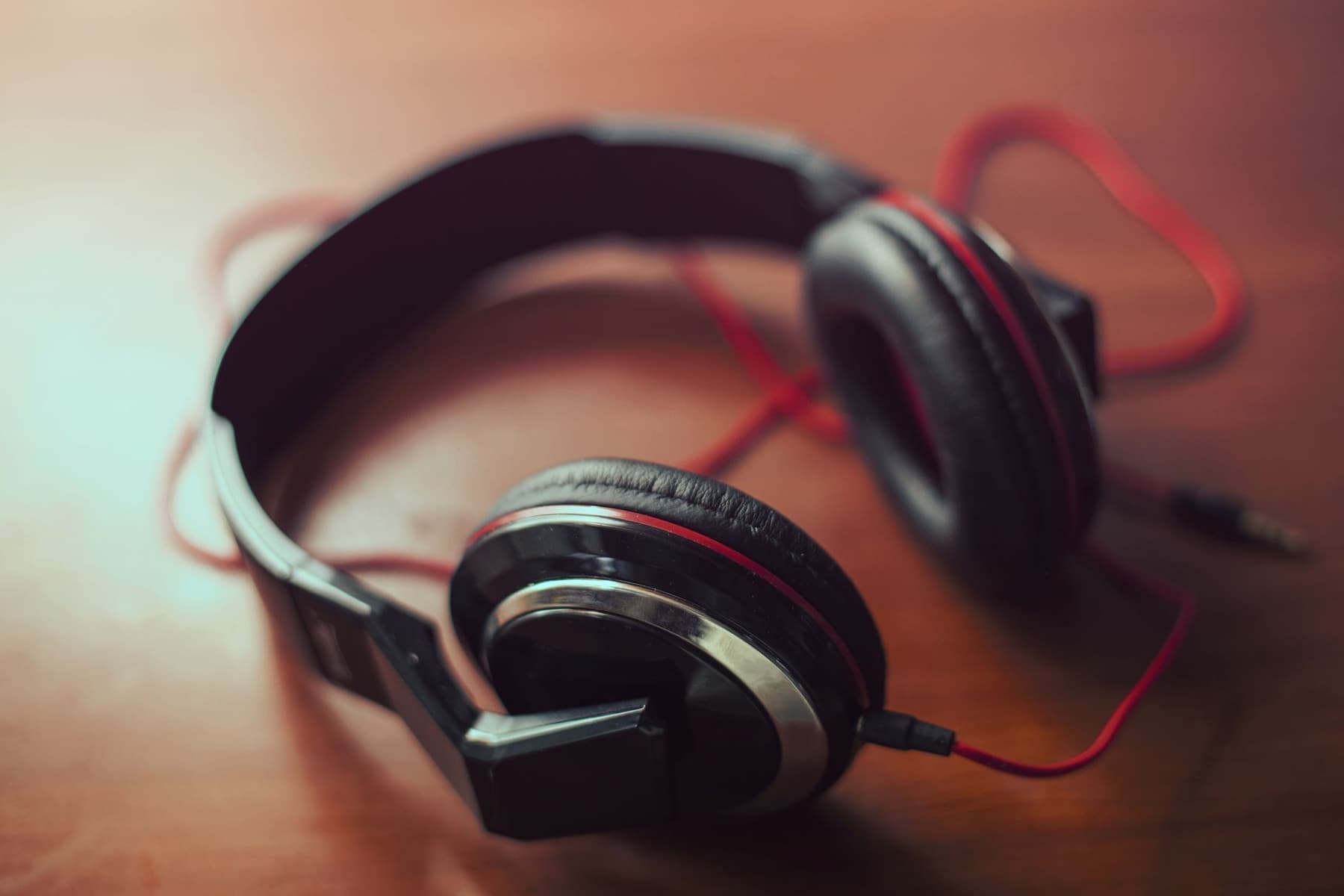 Two pairs of over-ear headphones on a wooden surface