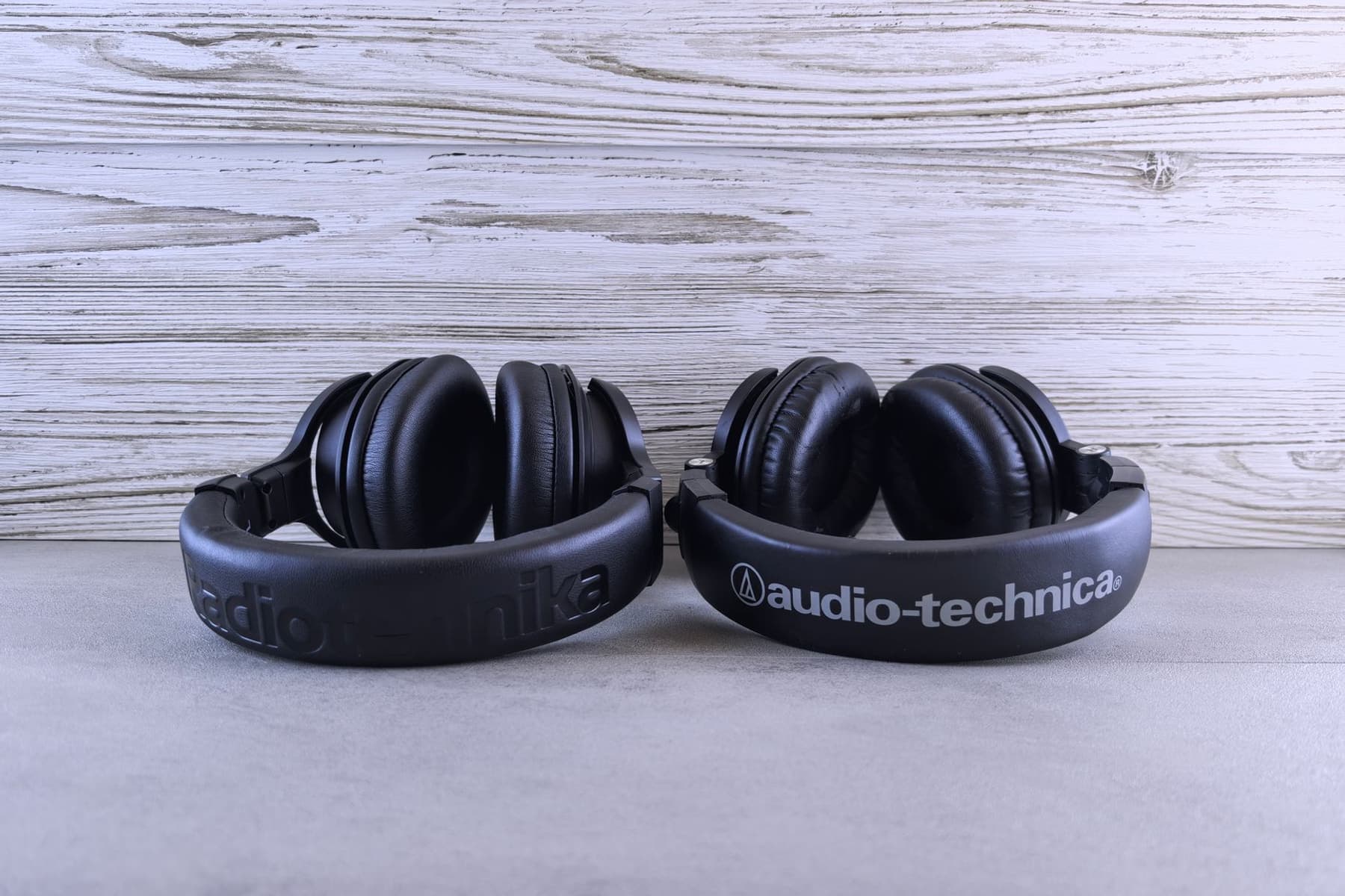 A pair of over-ear headphones photographed on a wooden desk
