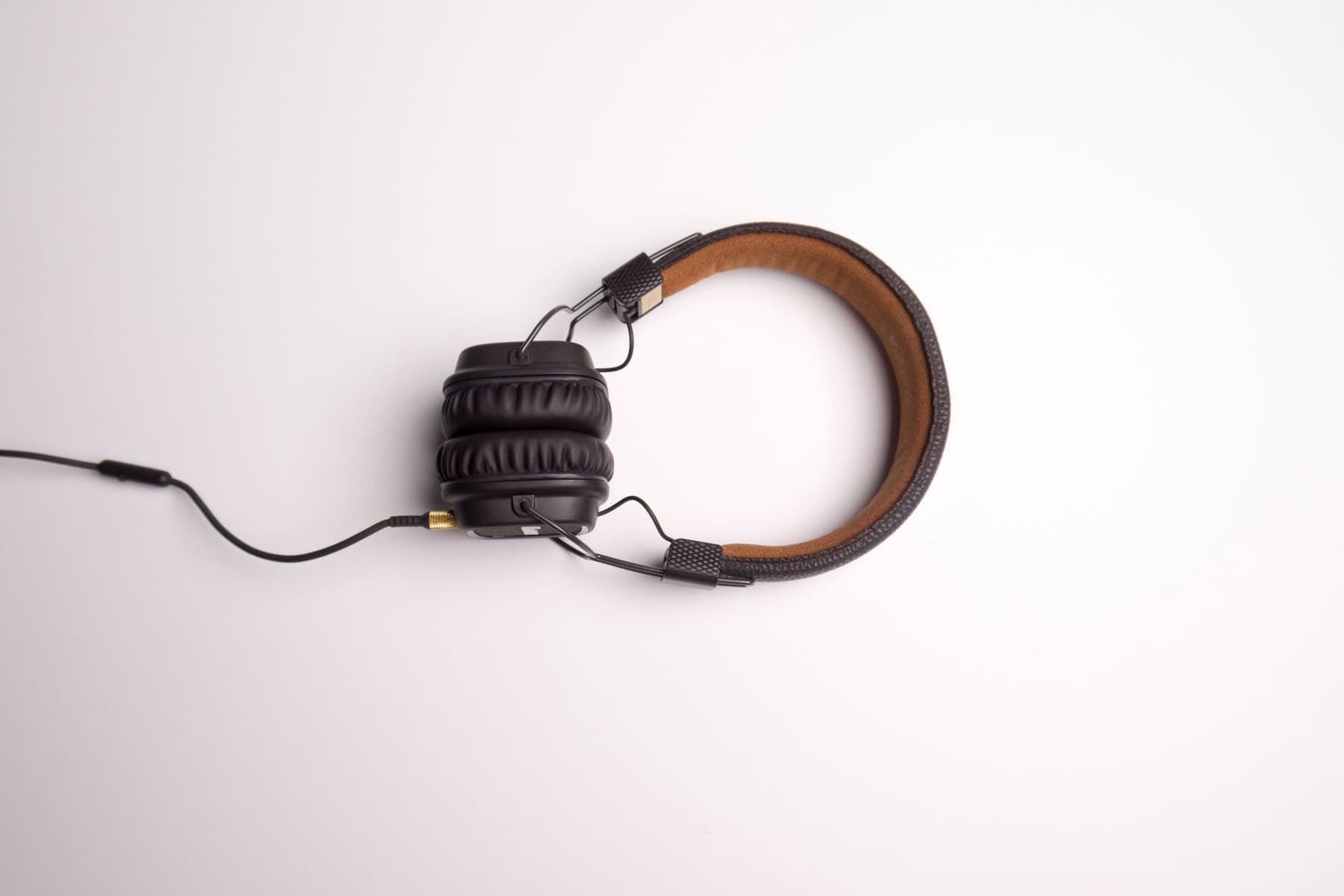 A pair of slim black over-ear headphones photographed on a white surface