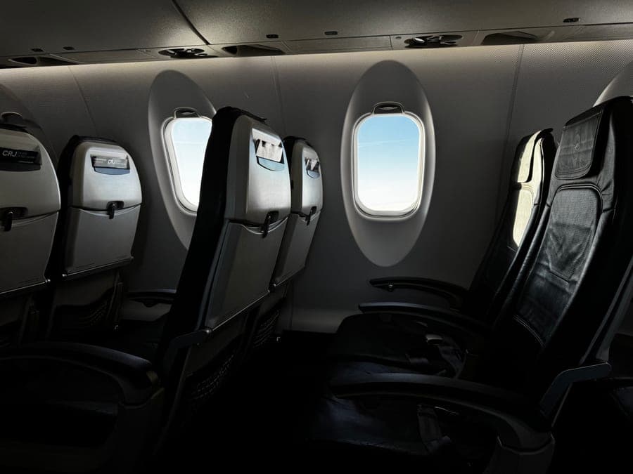Interior of an airplane cabin with bright sky visible through the window