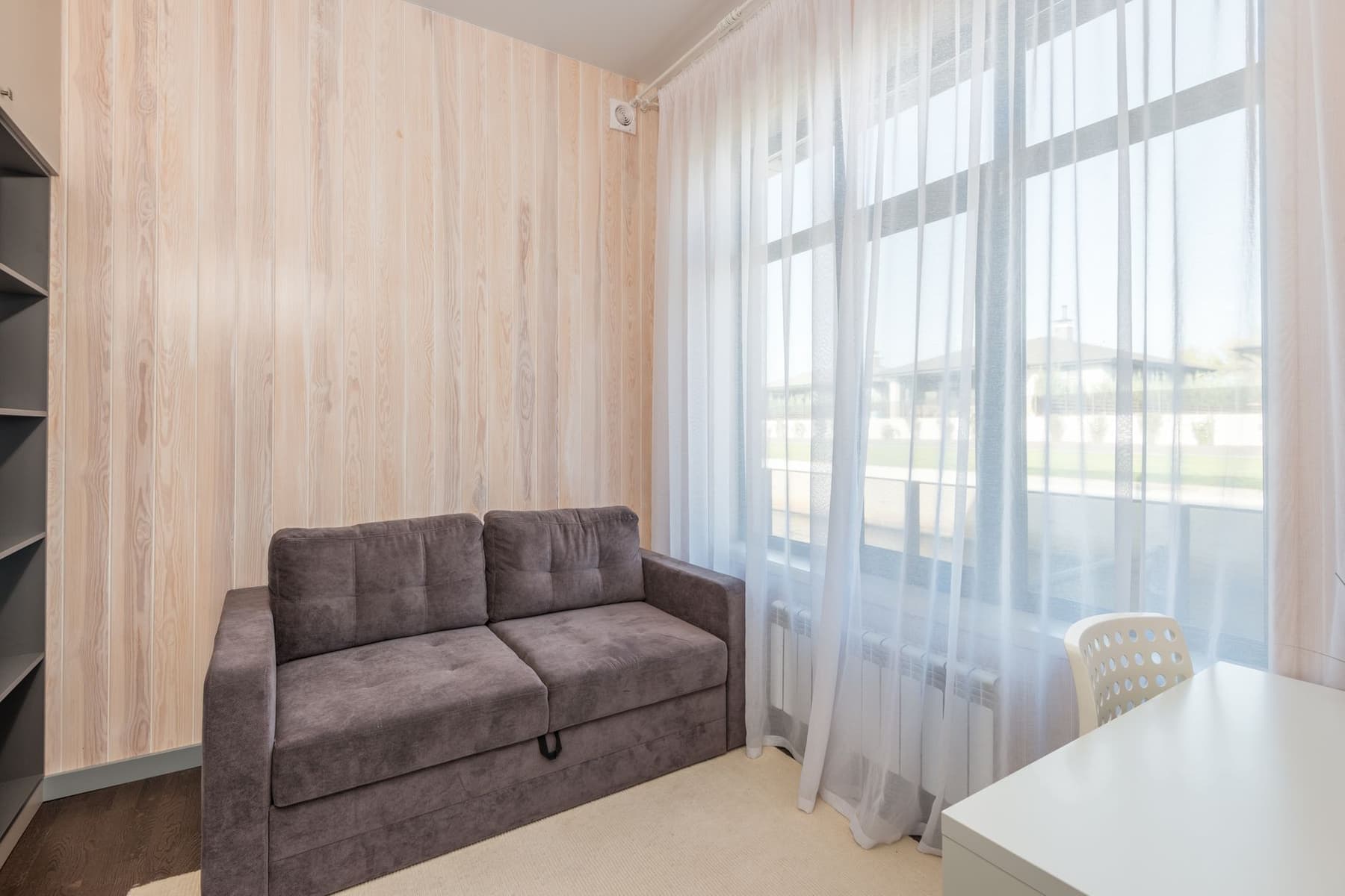 A bright apartment living room with a sofa and a large window