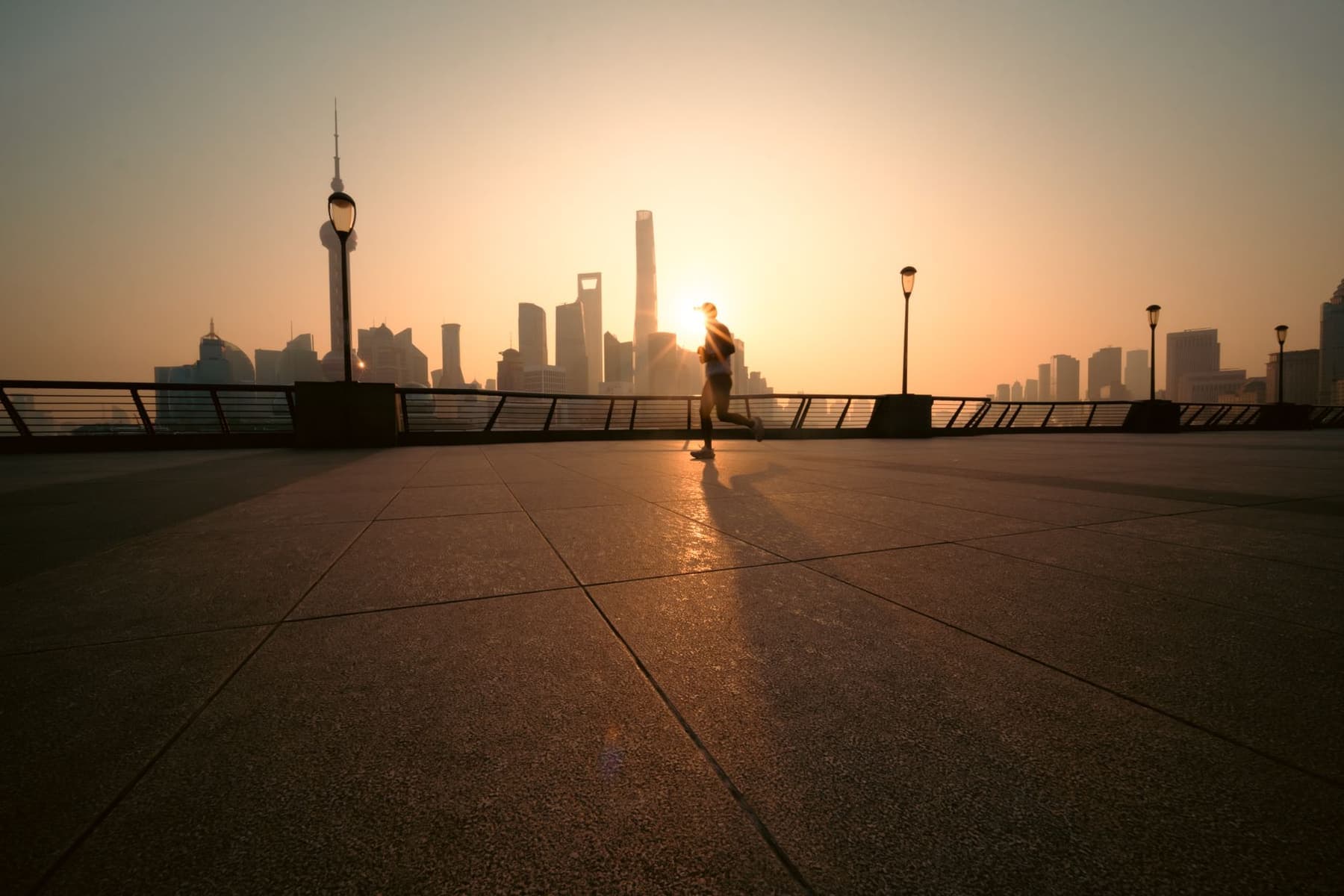 A runner on a city street path at sunrise