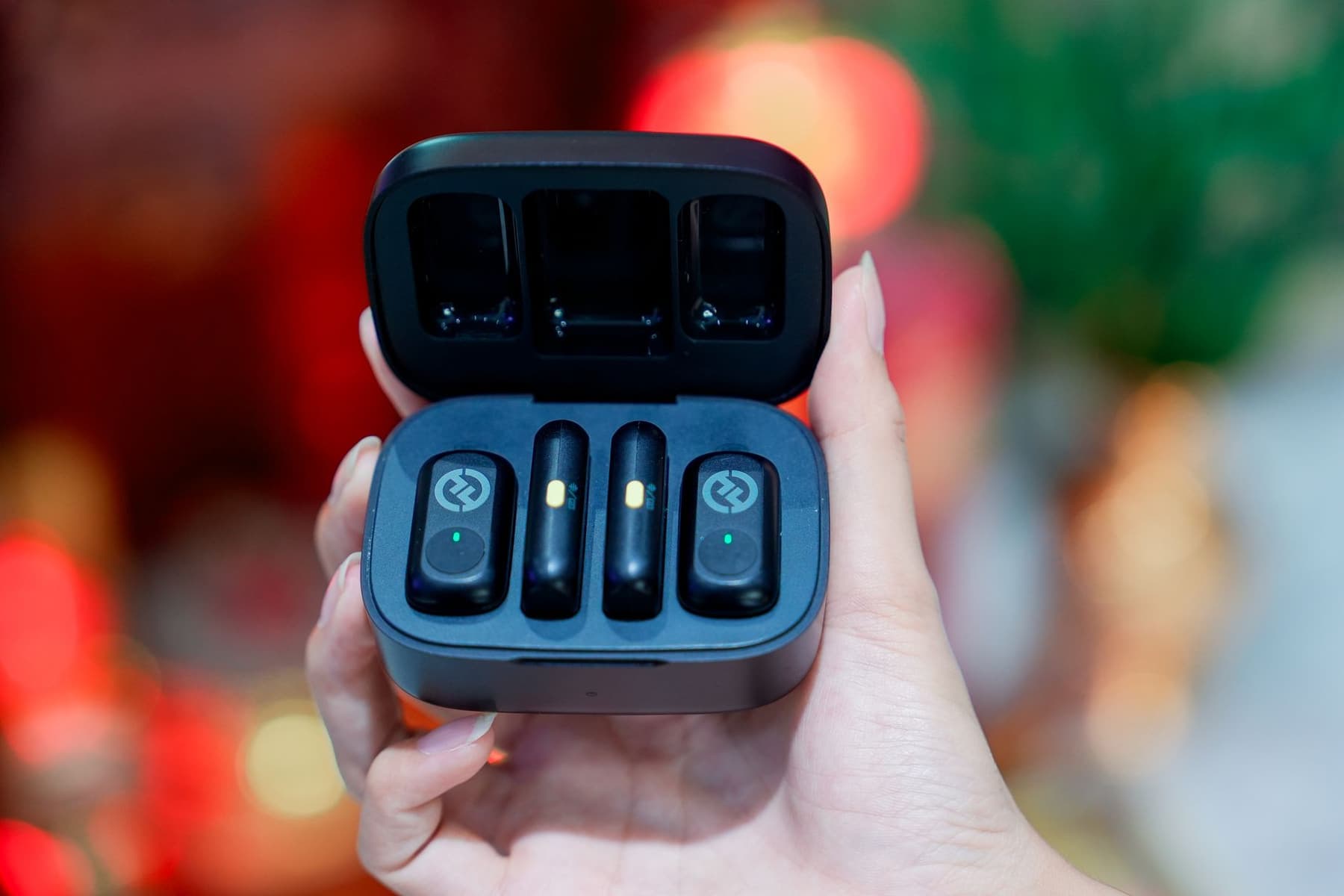 A hand holding a small wireless earbud charging case up close