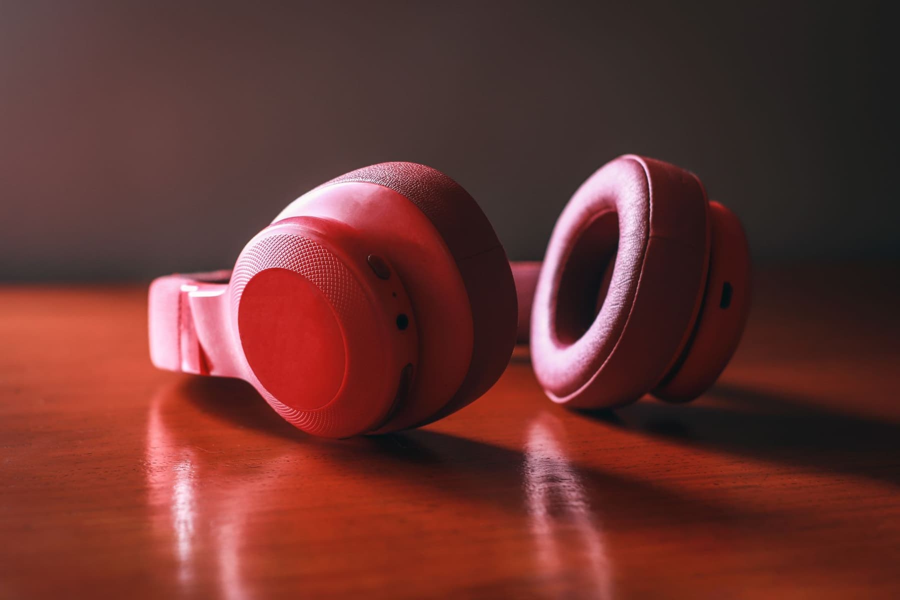 Close-up of a pair of wireless over-ear headphones resting on a wooden surface