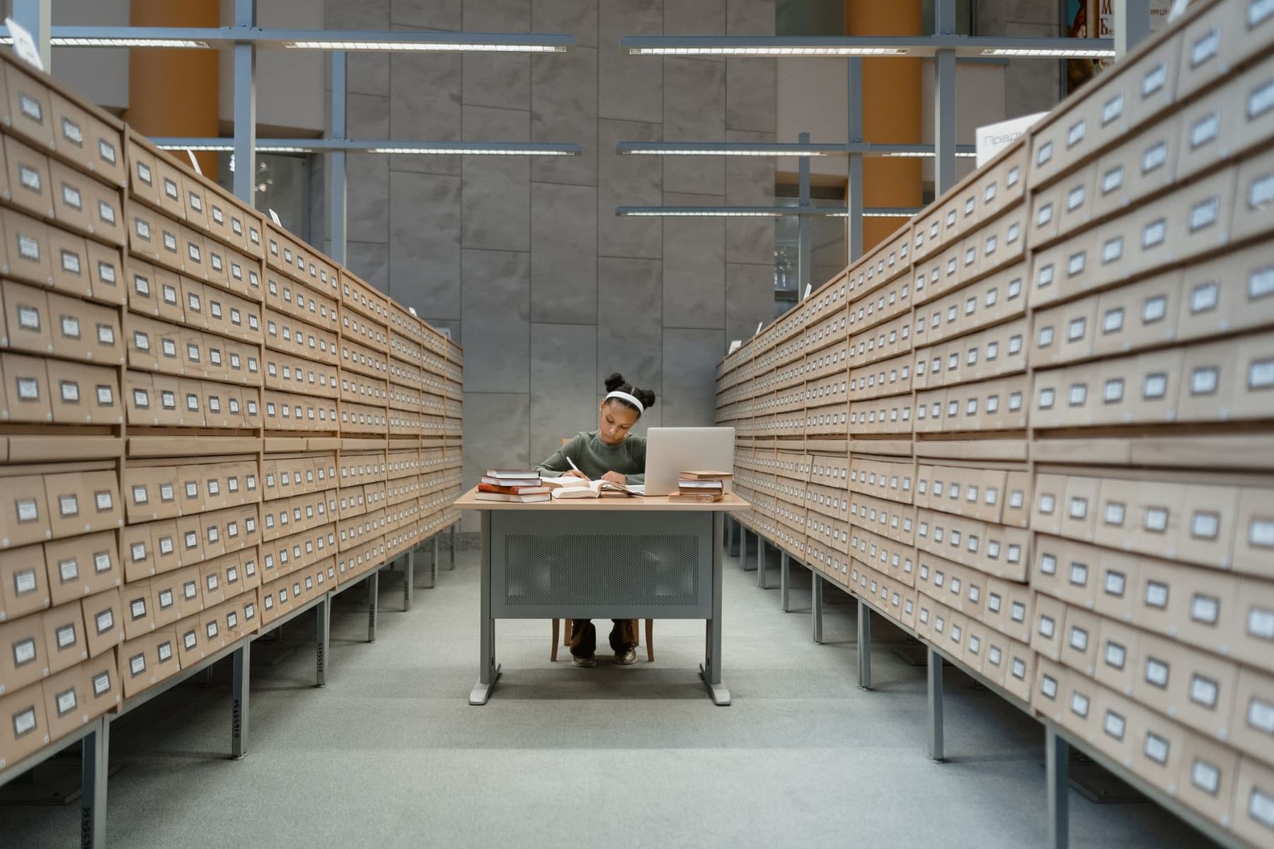 A student working at a desk surrounded by library card catalogs