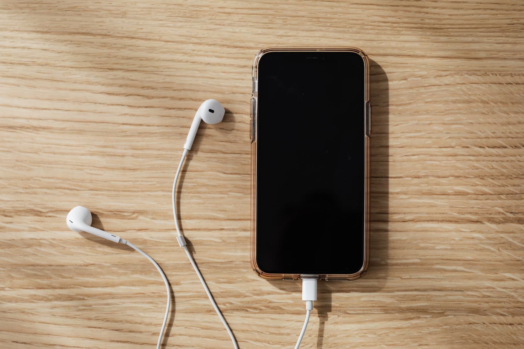 Simple wired headphones resting on a wooden table